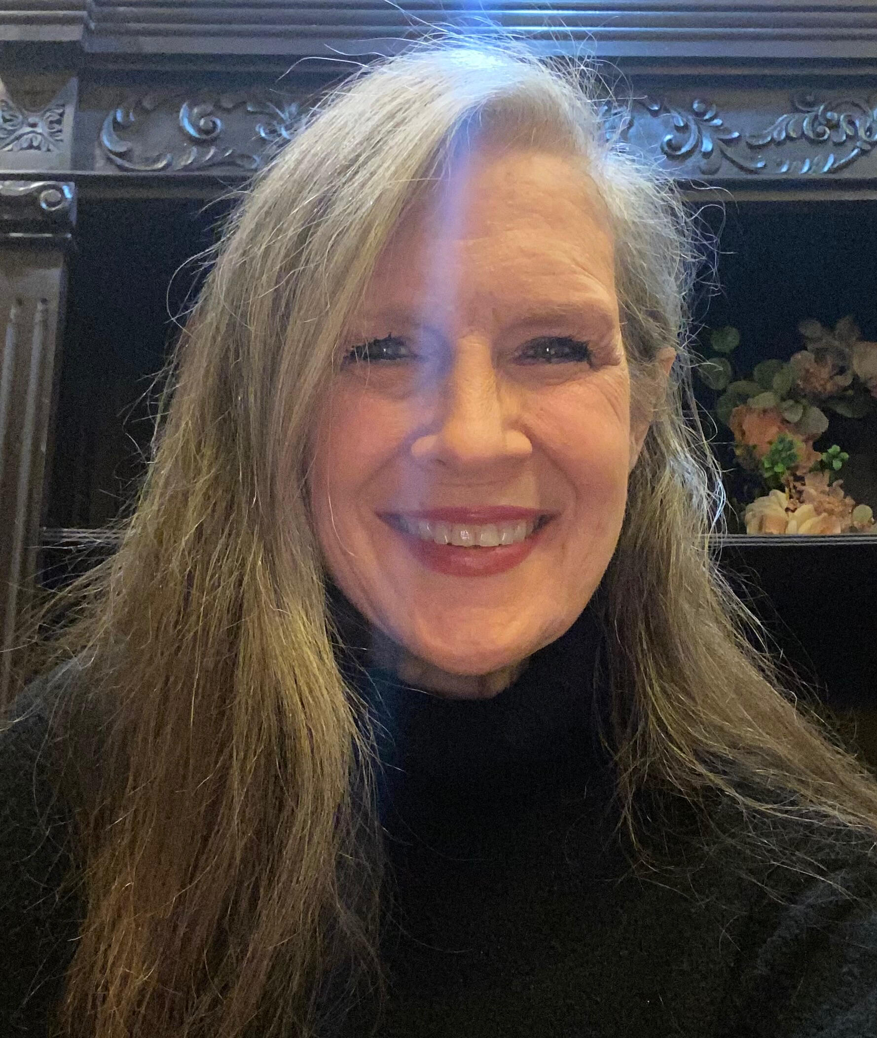 Casual photo of Refine Disabilities founder Donna Earnest. She is a white woman in her late 60’s, with shoulder length brown mixed with gray hair, wearing light makeup. She is smiling with joy. She is wearing a black pullover sweater.