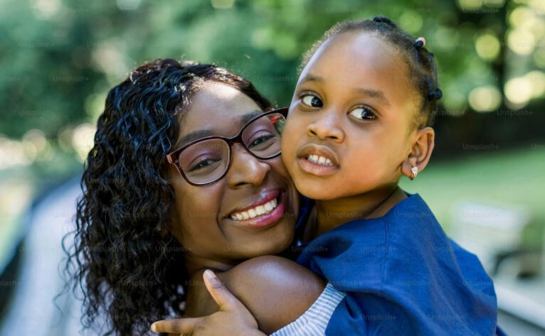 Smiling black woman hugging her little girl about 5 years old